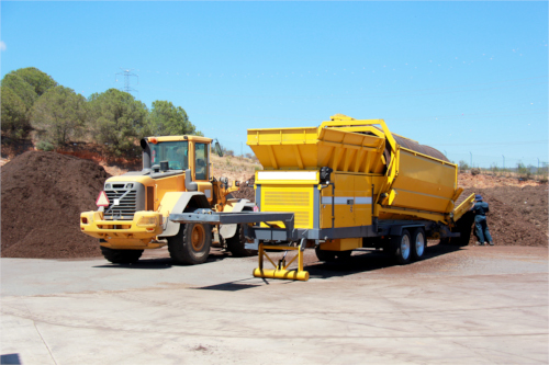Two yellow industrial trucks in a recycling yard